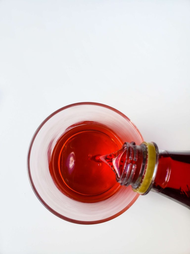 Above view of someone adding grenadine to glass. 