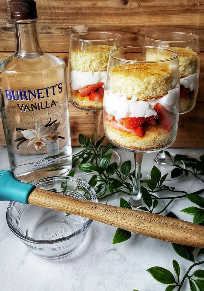 Completed recipe of strawberry shortcake with fruit whipped topping and cake next to alcohol bottle