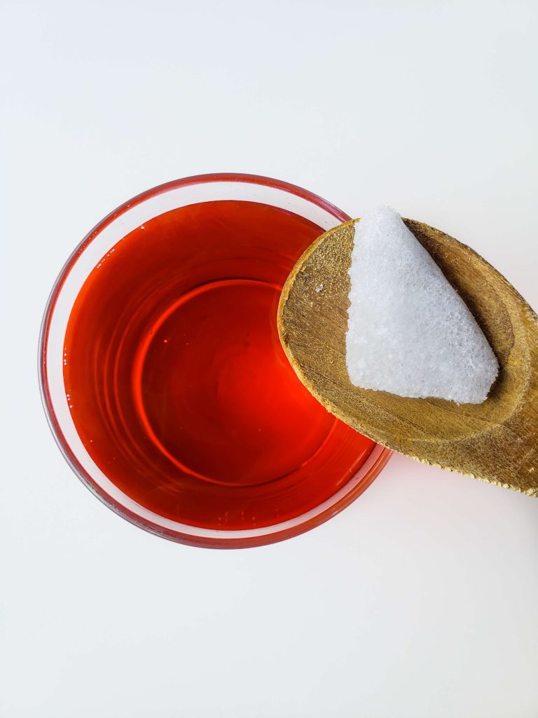 Above view of someone adding dry ice with a wooden spoon to cocktail. 