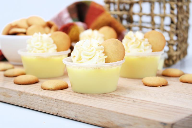 Boozy Banana Cream Pie Jello Shots Recipe in plastic shot cups with nilla wafers and cream