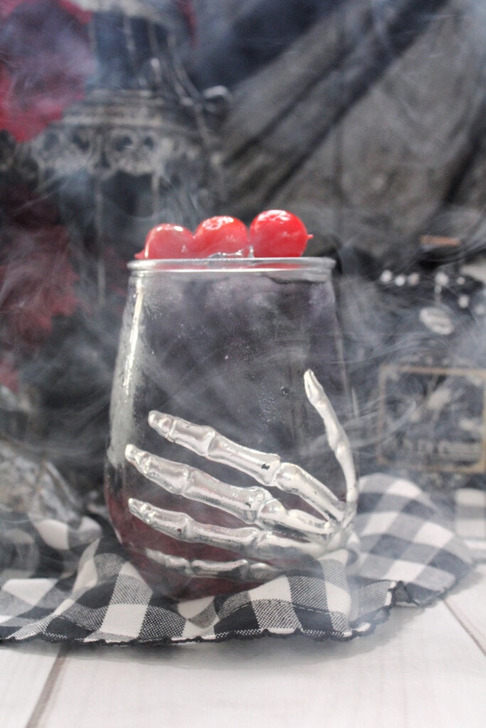 cocktail in a skeleton hand glass with mist around it to give it an eerie look. 
