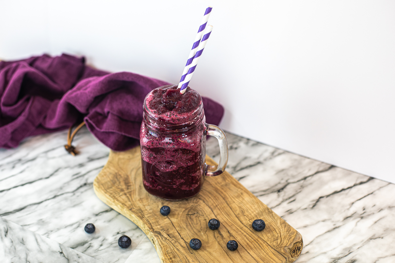 Blended Blueberry Daiquiri on a wooden slab with blueberries around it 
