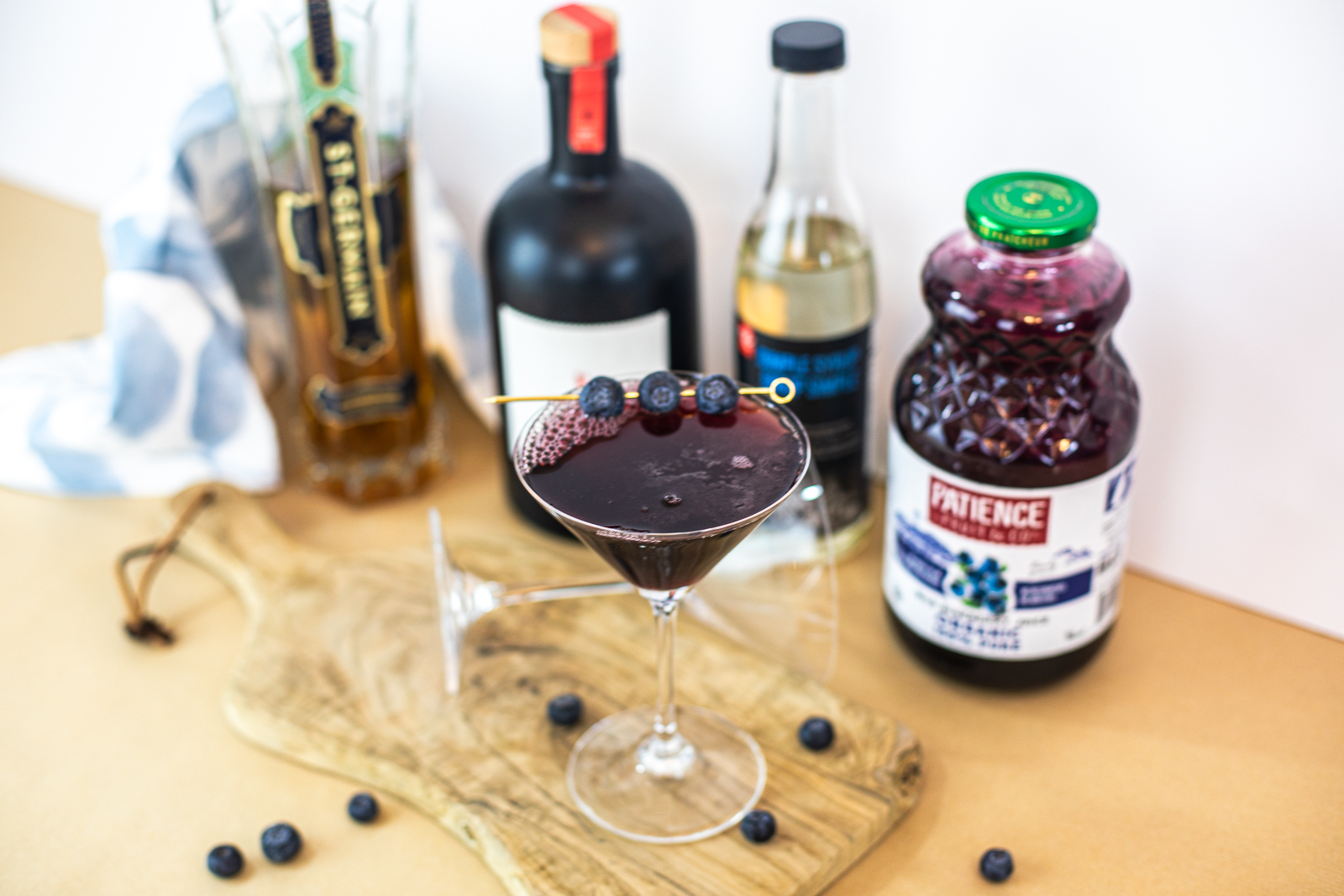 Completed dark purple cocktail with fresh blueberries as garnish. 