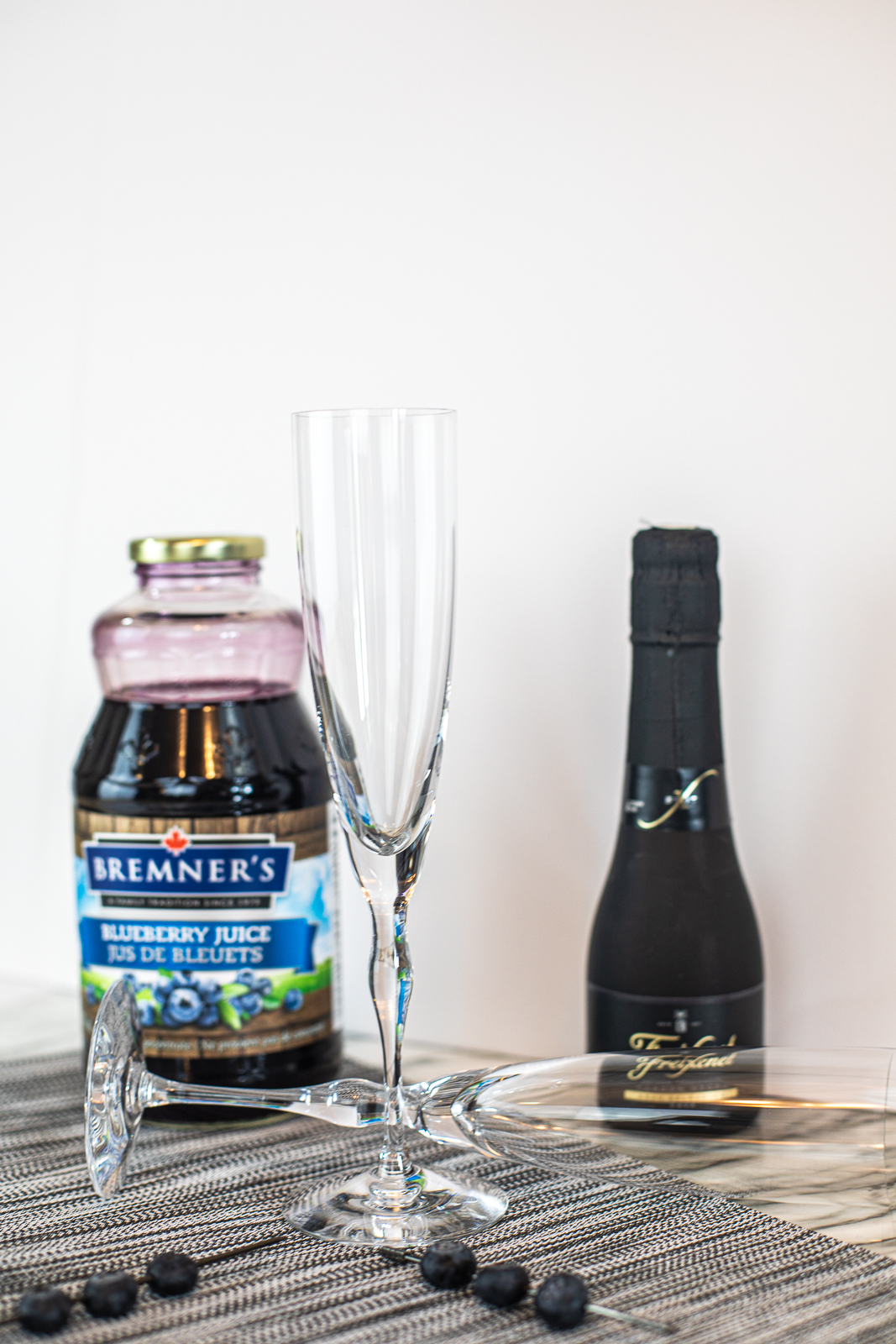 Picture showing ingredients: blueberry juice, sparkling wine, and two wine flutes. 