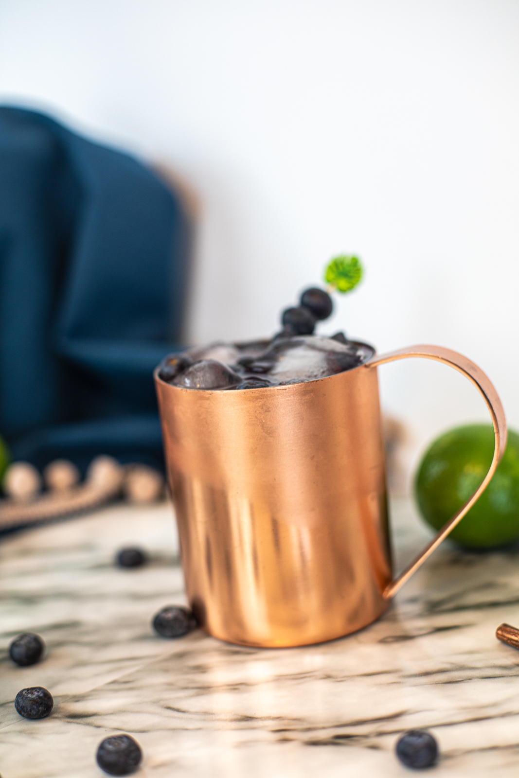 Close up of a copper mug with ice and blueberries on top. 