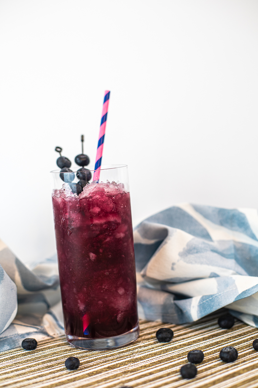 dark purple cocktail topped with fresh blueberries. 