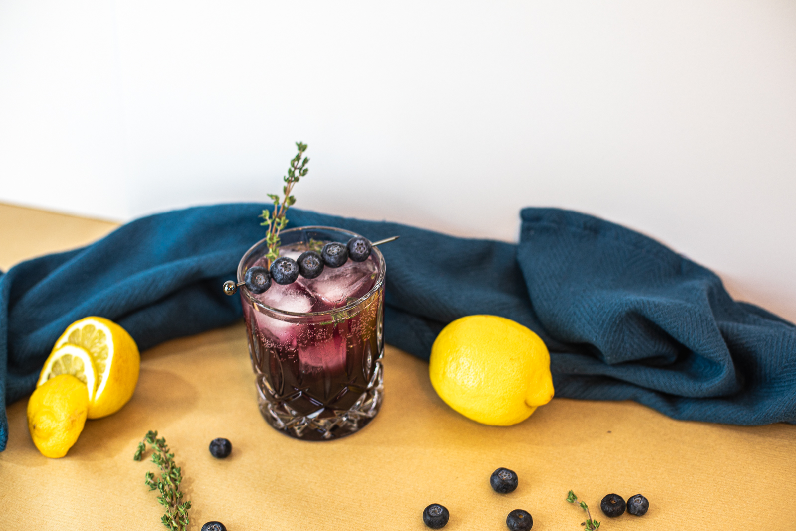 cocktail with navy cloth behind and a few lemons. 