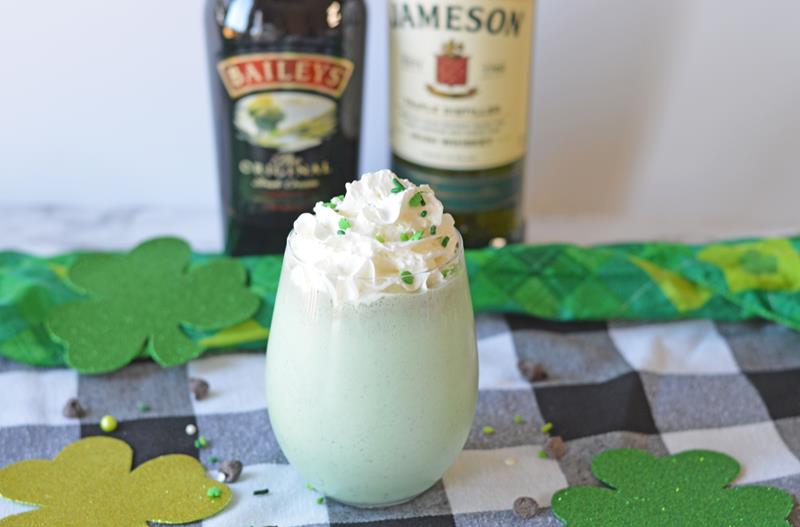 close up of boozy shamrock shake on black and white table cloth with shamrock cut outs 