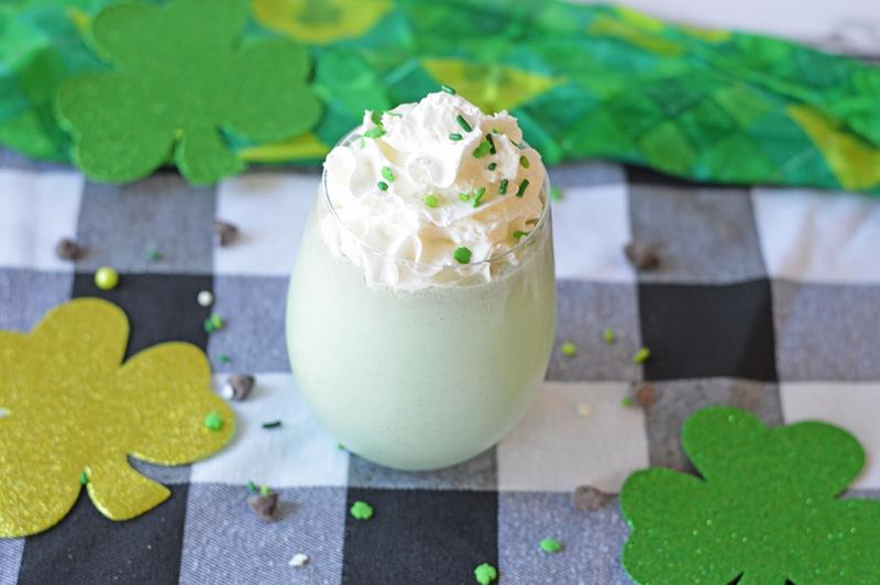 showing finished drink in clear glass with whipped cream and green sprinkles 
