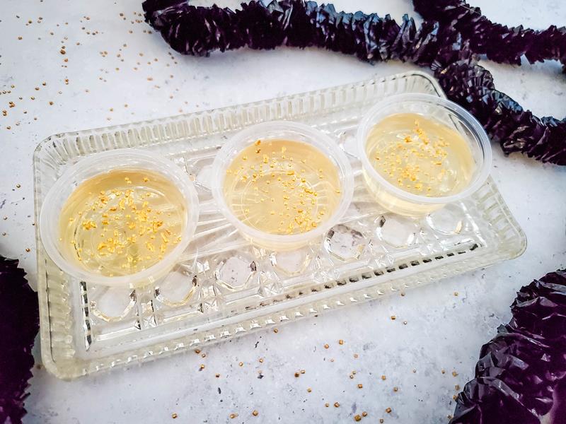 champagne jello shots with gold glitter on a marble tabletop