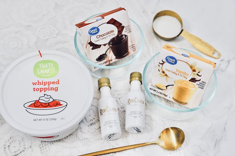 Ingredients required to create your shot: whipped topping, chocolate pudding in a clear bowl, vanilla pudding in a clear bowl, and two small bottles . 