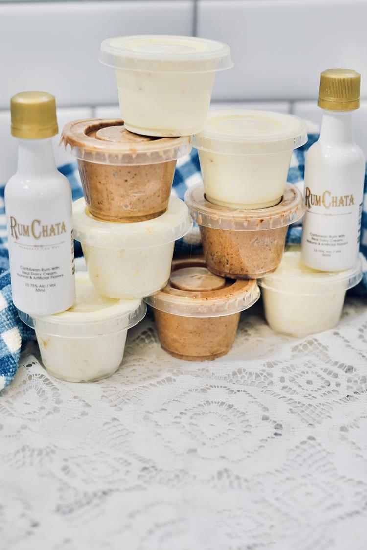Close up of condiment cups with some brown chocolate ones and some white vanilla ones with two small bottles of Rum Chata beside them. 