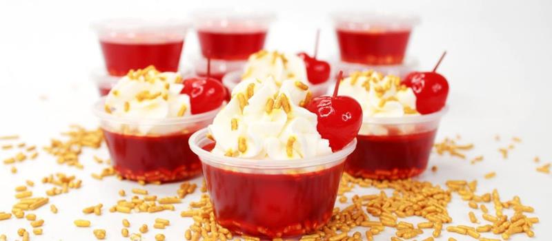Cherry jello shots with whipped cream topping and maraschino cherries
