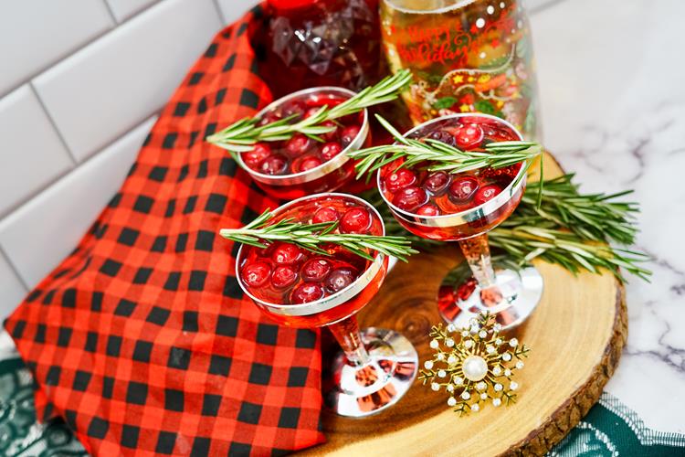 Three cocktails with cranberries and rosemary as garnish. 