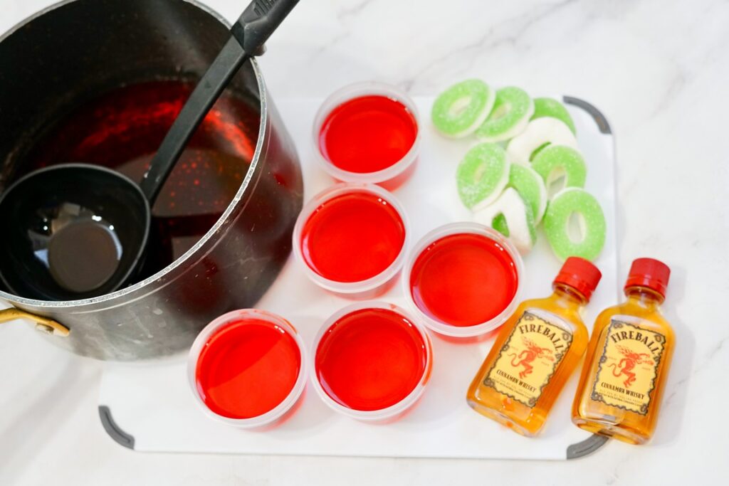mixutre being put into jello shot plastic cups. 