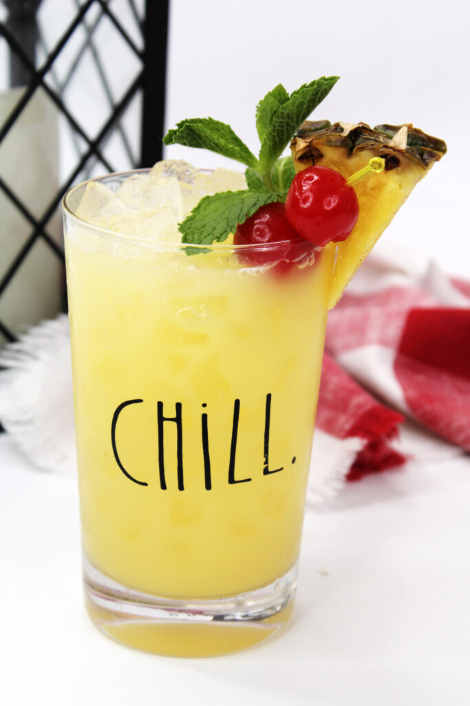 Picture of a Disneyland inspired cocktail with pineapple and cherry garnish in a tall glass