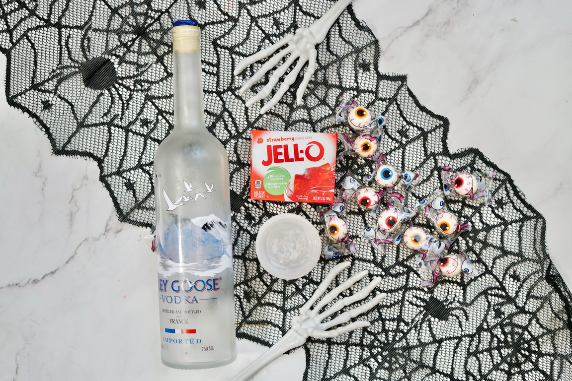 Ingredients needed for eyeball jello shots - vodka bottle, strawberry jello mix, and eyeball gummies. 