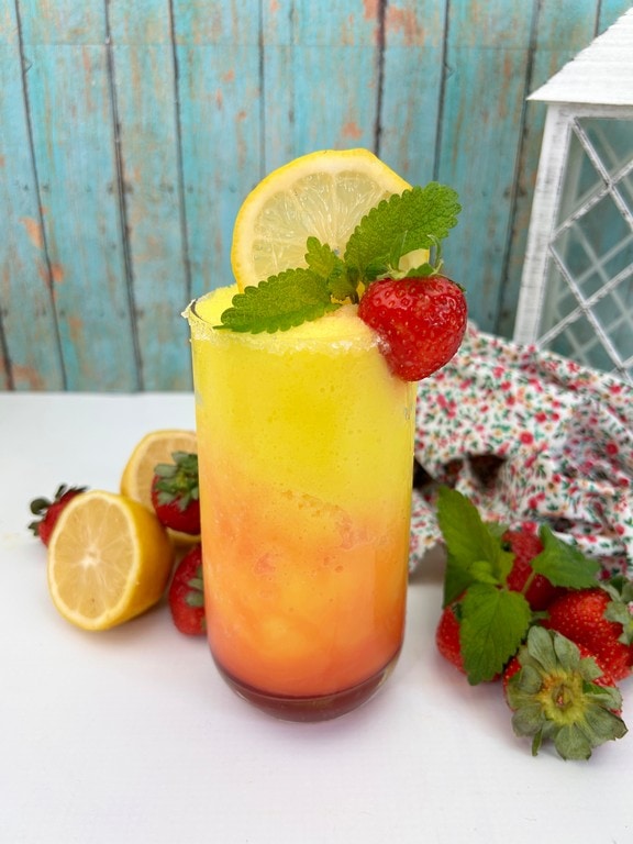 Frozen Strawberry Lemonade Cocktail - Cocktail with fresh strawberries and lemons all around it. 