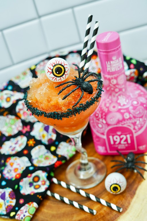 Halloween Strawberry Margarita - close up of spooky garnish of plastic yellow eye ball and plastic black spider. 