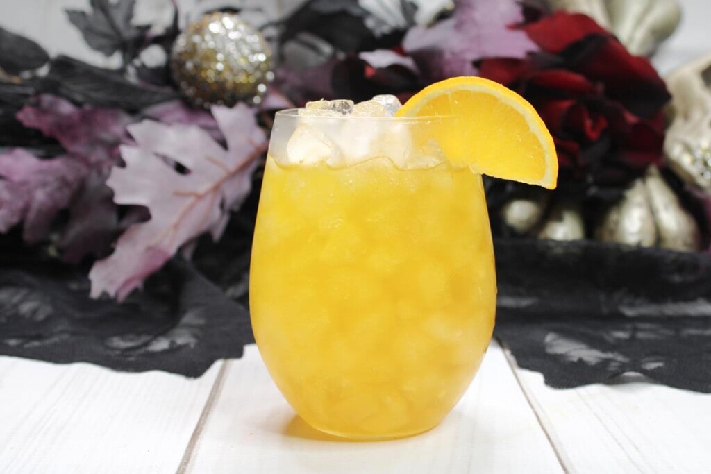 Showing finished howling wolf cocktail with ice and lemon wedge 