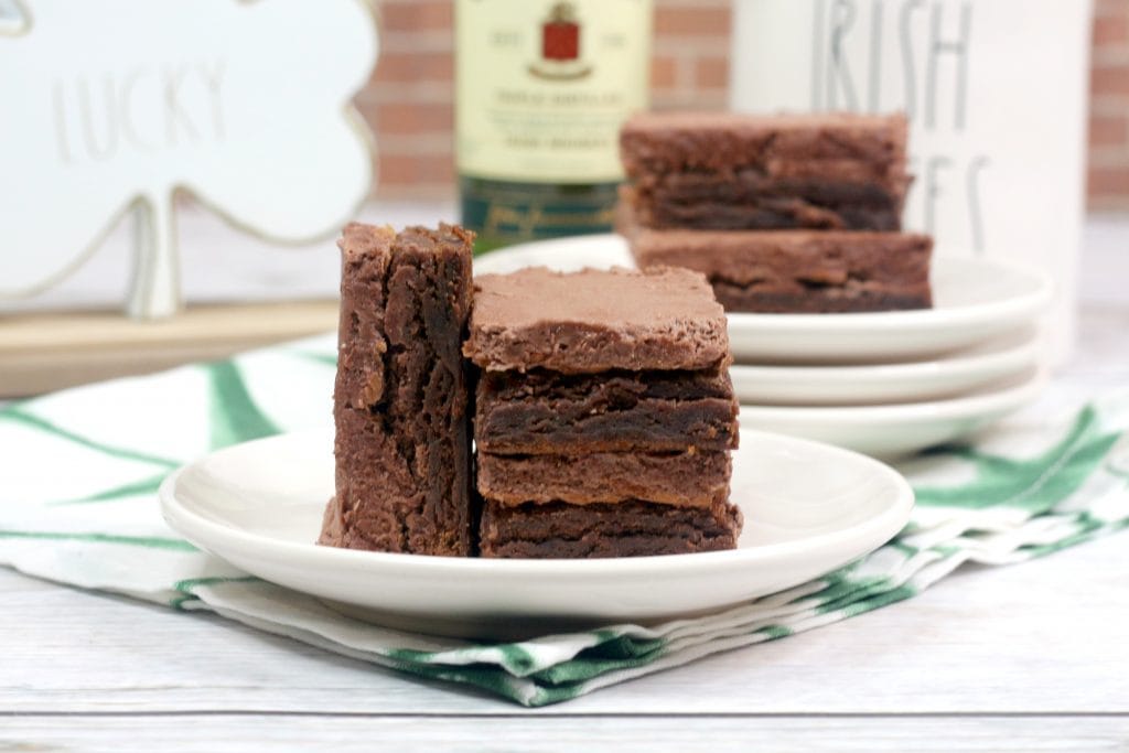 brownies on white plate with whiskey bottle in background
