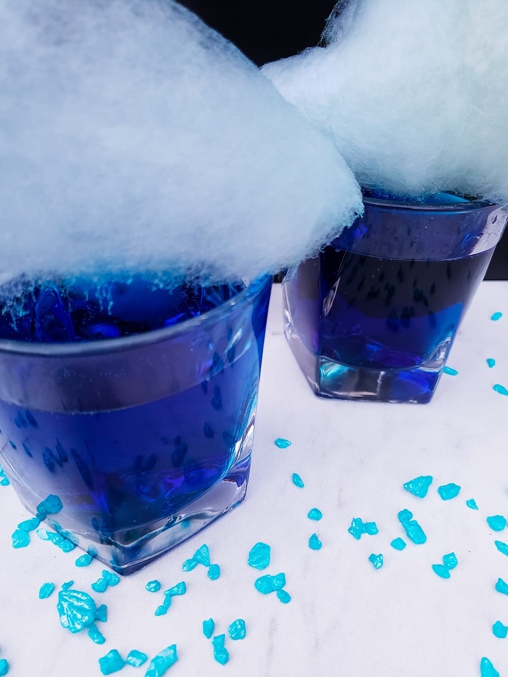Two completed Genie Juice Cocktails with large pieces of light blue cotton candy on top. 