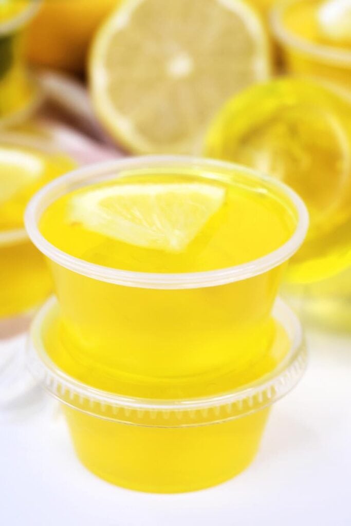 close up of two jello shots stacked on top with a lemon wedge piece on top 