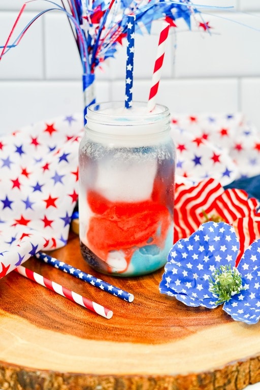 Delicious Patriotic Float For Kids - close up of clear jar style glass with sprite and red, white, and blue sorbet in it. 