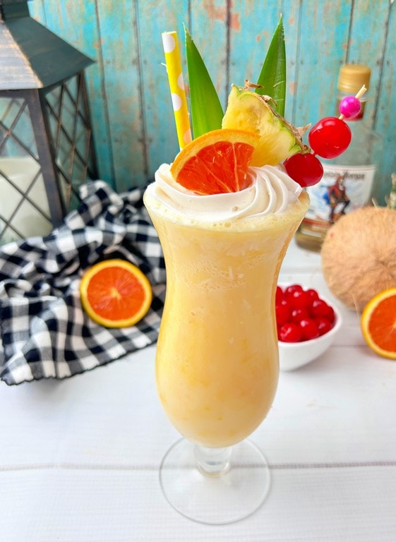 Close up of drink with orange, pineapple, and cherries as garnishes. 