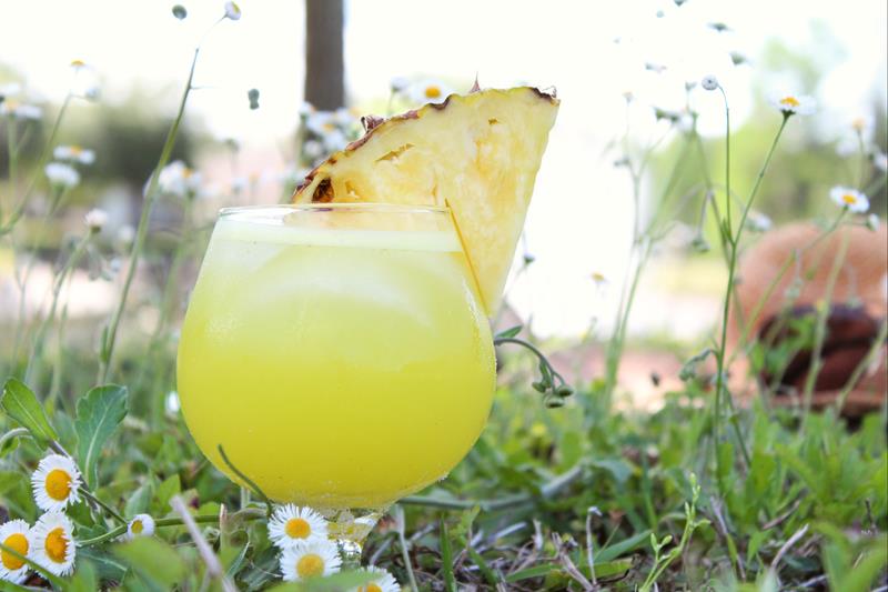 close up of yellow drink with large pineapple wedge 
