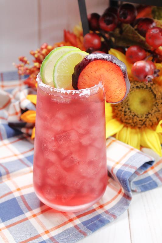 Plum Margarita Recipe: showing close up of completed margarita with sunflowers in the background. 