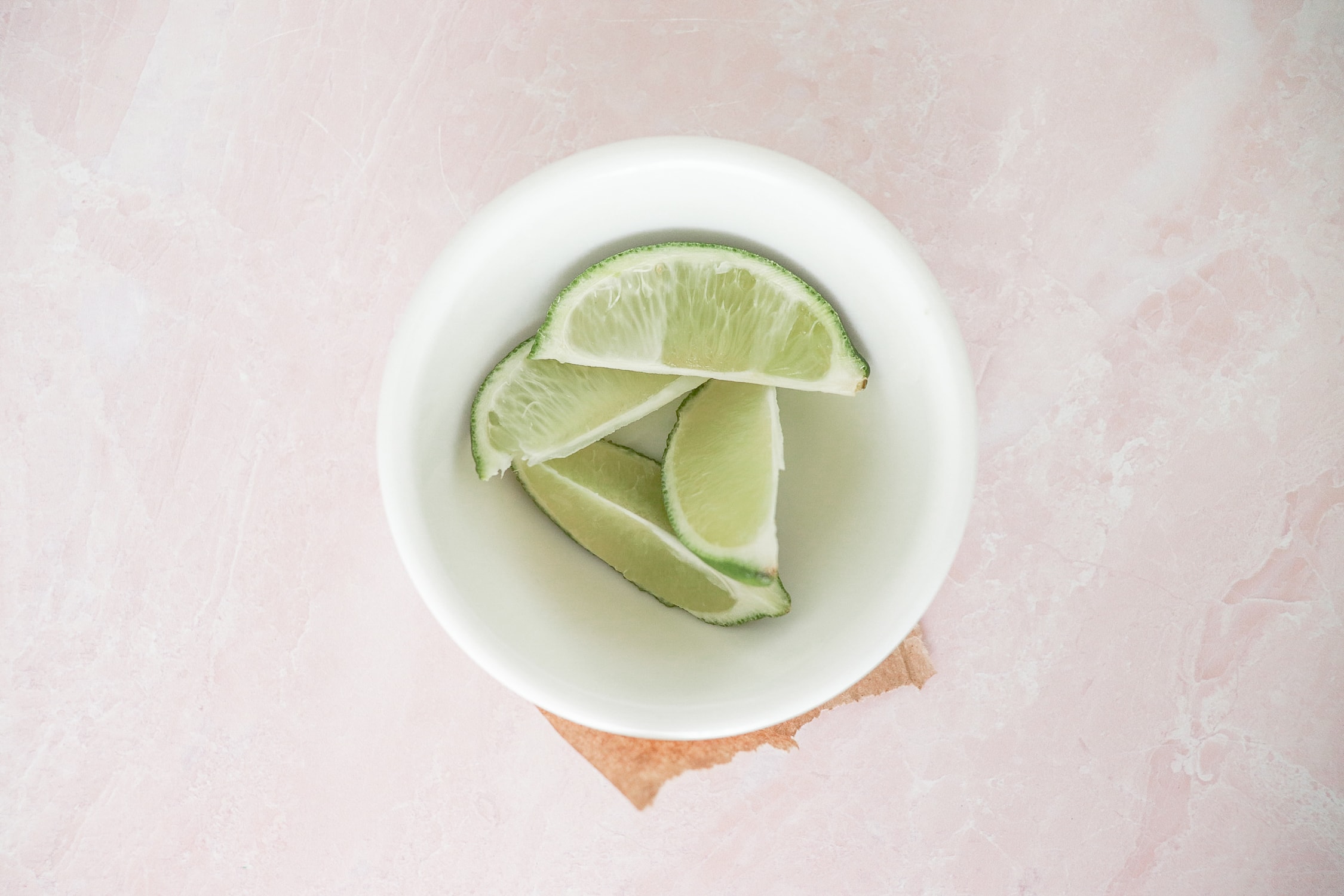 Above view of white bowl with 4 lime slices in it. 