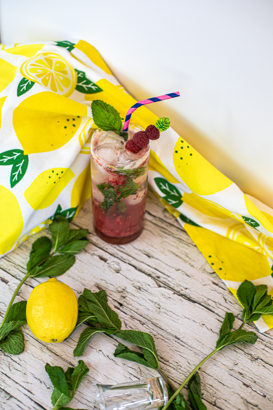 Drink with three raspberries and a mint leaf as garnish. 