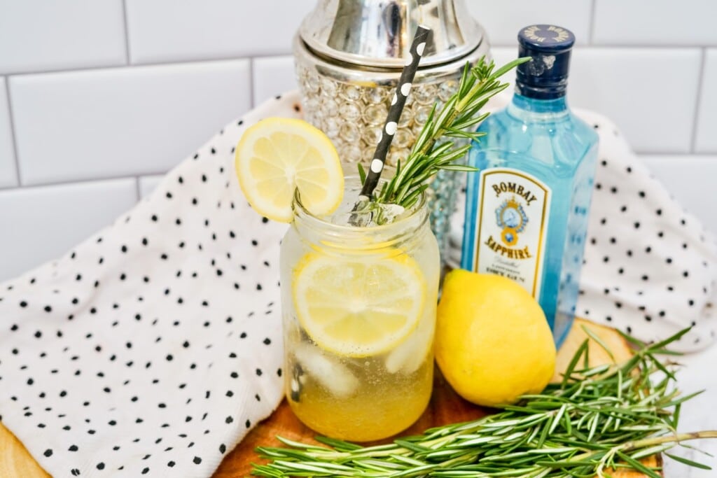 Rosemary Gin Fizz - Drink in a clear jar with lemon slices and rosemary garnish.