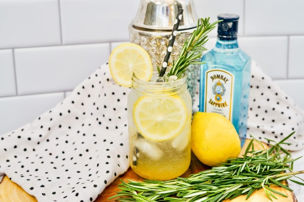 Fresh Rosemary and lemon beside a completed cocktail. 