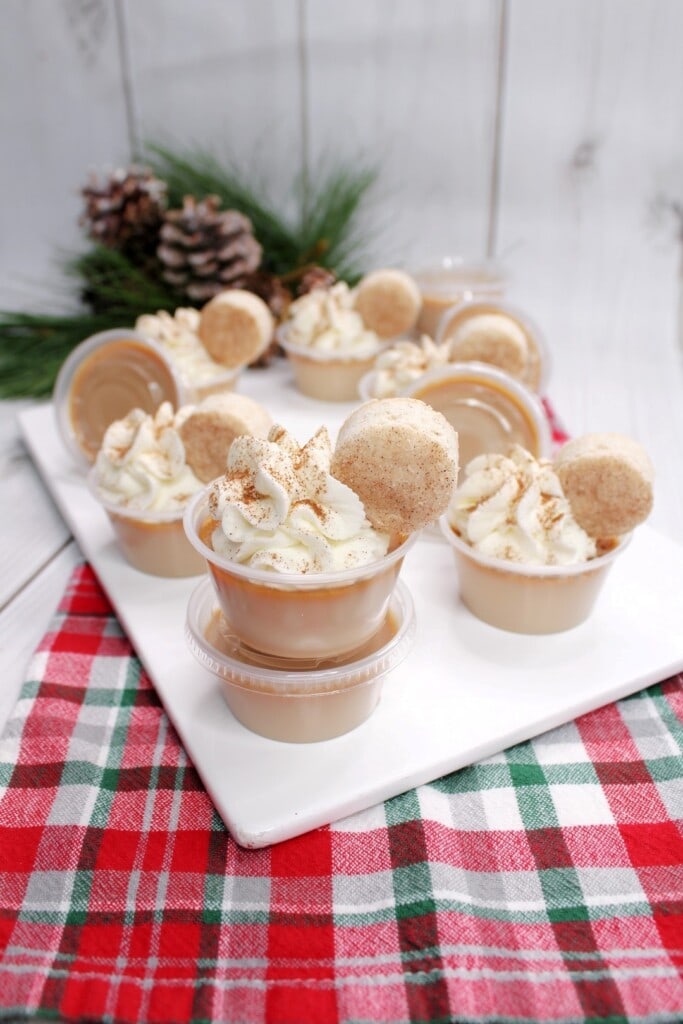 white plate full of Snickerdoodle Jello Shots all topped with whipped cream, cinnamon and mini snickerdoodle cookies. 