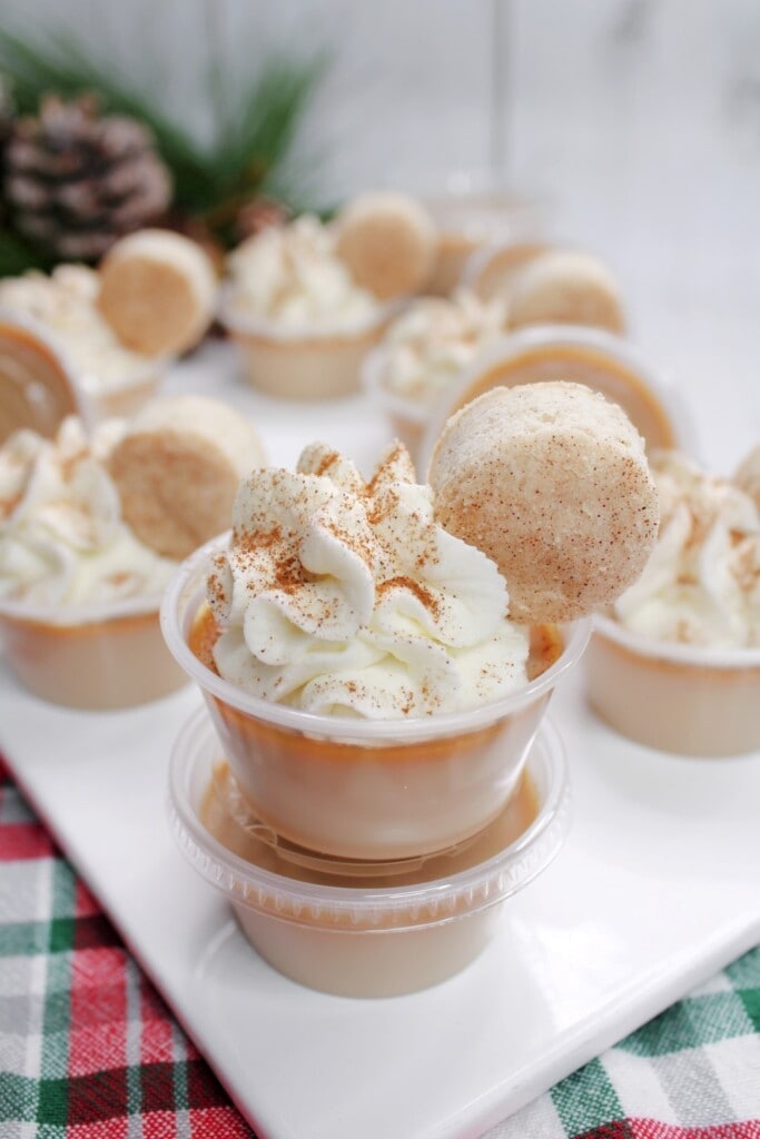 Close up of snickerdoodle jello shot with whipped cream, cinnamon sprinkled on top and a mini snickerdoodle cookie. 