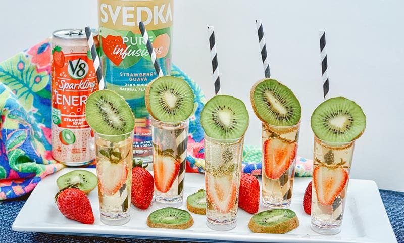 five completed strawberry kiwi shooters, filled with strawberry and half a kiwi on top 