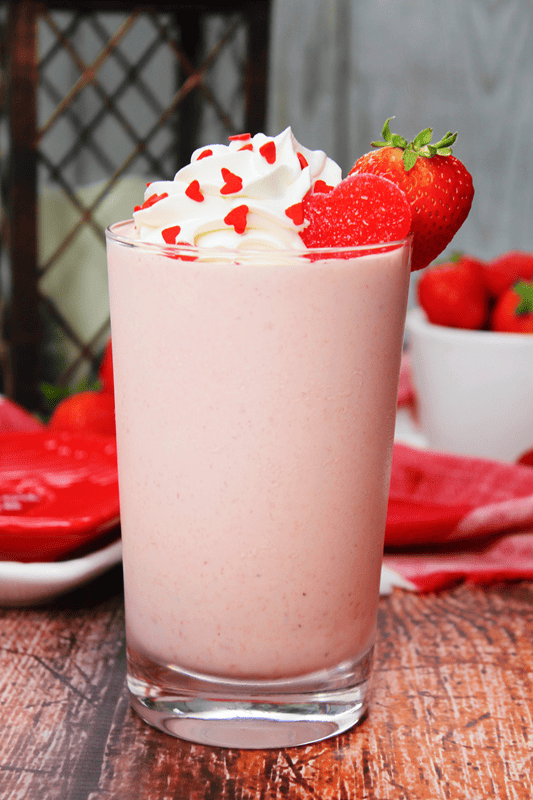 Pink creamy milkshake with whipped cream and strawberry. 