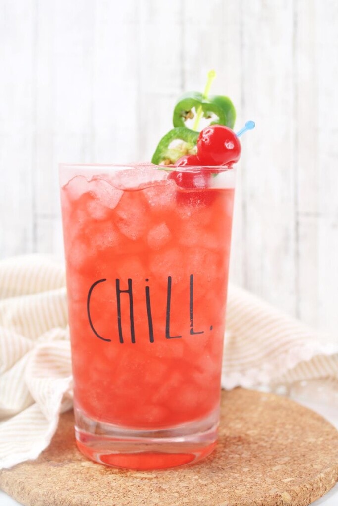 Finished cocktail in glass that says CHILL, with cherries and jalapenos as garnish 