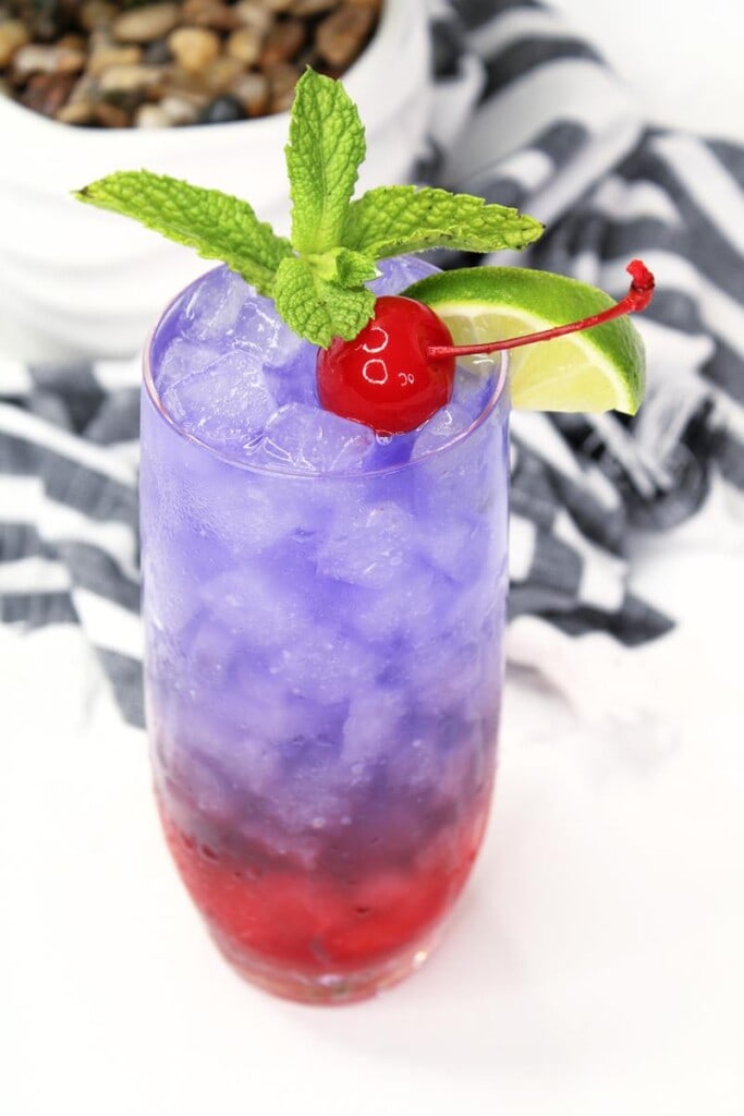 top of purple fade drink showing mint, cherry, and lime wedge as garnish 