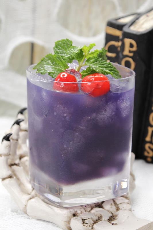 Clear glass filled with lots of ice and a dark purple drink. 