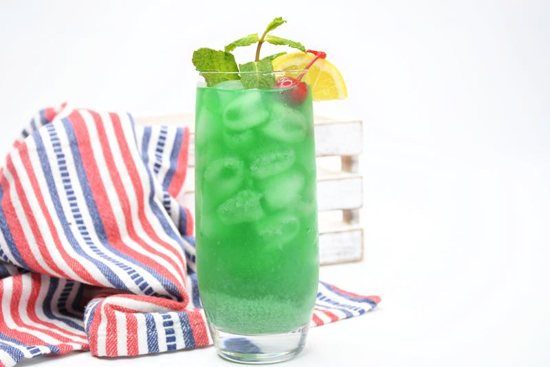 close up of cocktail, green with ice and garnish on top 