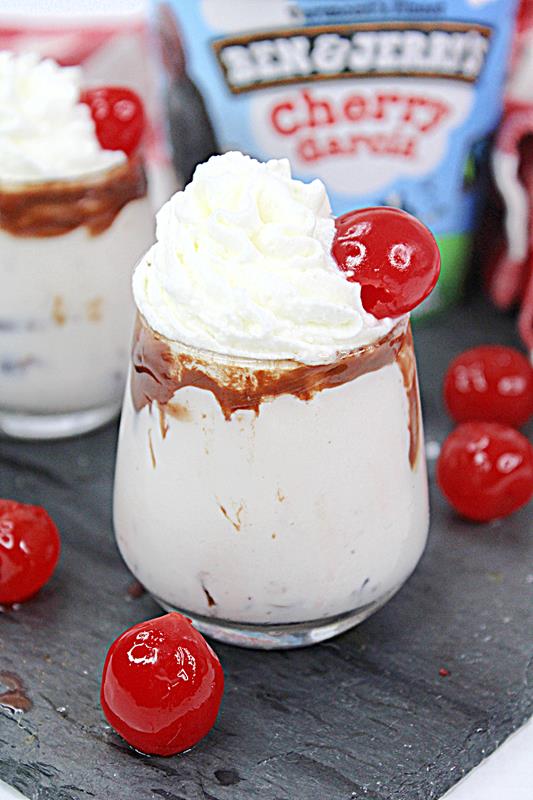 Close up of Cherry Garcia Ice Cream Shooter showing whipped cream and one charry on top. 