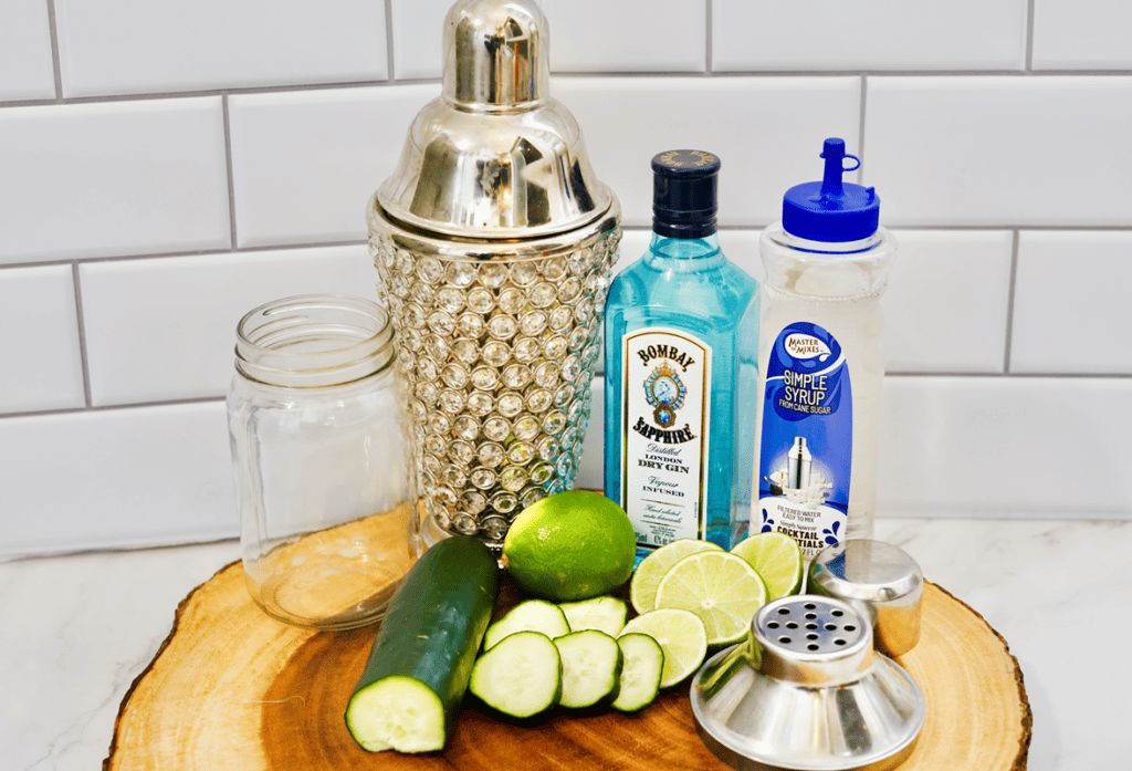 Ingredients required for cocktail: jar, cocktail shaker, gin bottle, simple syrup bottle, lime, cucumber. 