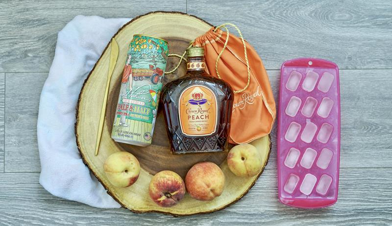 above view of four peaches, pink ice cube tray, peach crown royal, and peach tea 