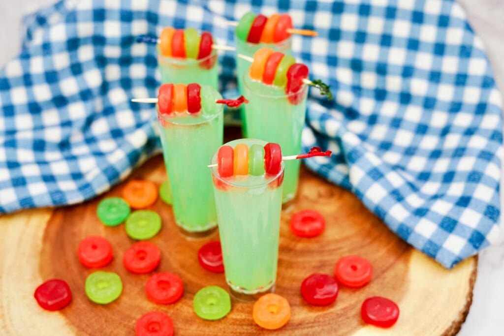 Lifesaver Gummy Shooter Recipe - Five shooters on a round wooden board with gummies all around. 