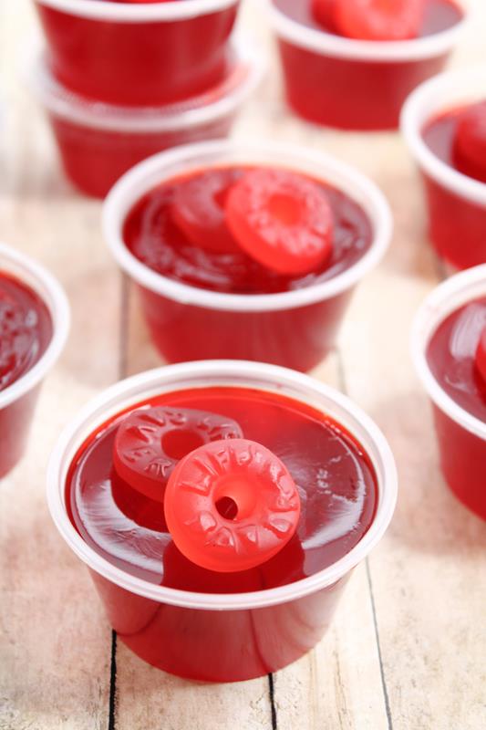 close up of red jello shots completed with two life saver gummies on top. 