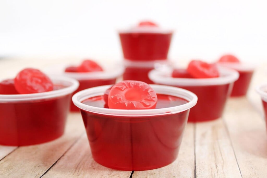 front view of completed red jello shots with two gummy lifesavers on top. 