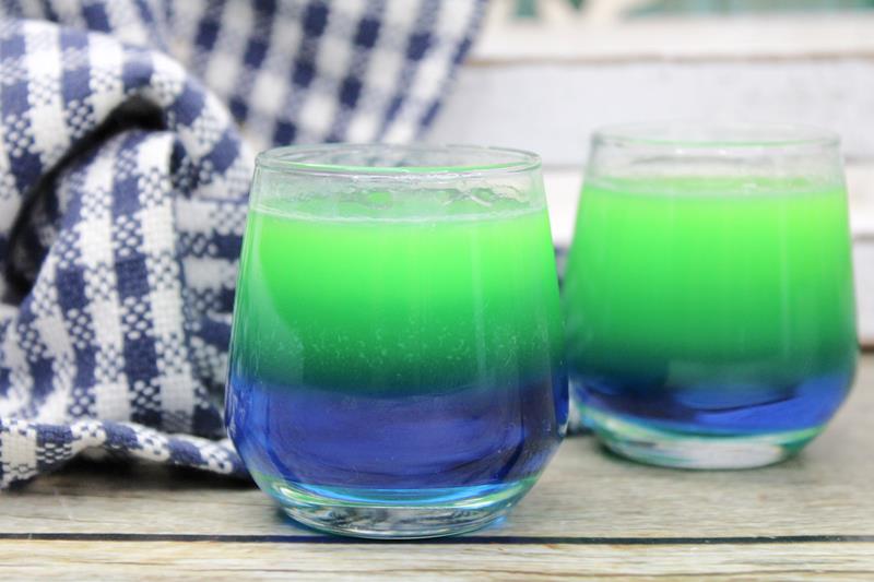 two clear glasses with blue at the bottom and green at the top. 